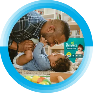 A father is looking at his baby. A package of Pampers Baby-Dry diapers is in the background.