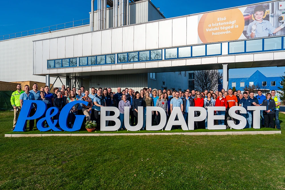 Dozens of employees outside the P&G Budapest site, all standing behind an installation that reads “P&G Budapest.”