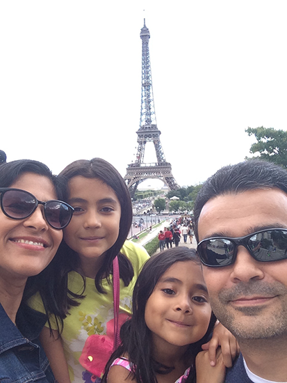 A man, woman and two young girls post together. The Eiffel Tower stands in the background.