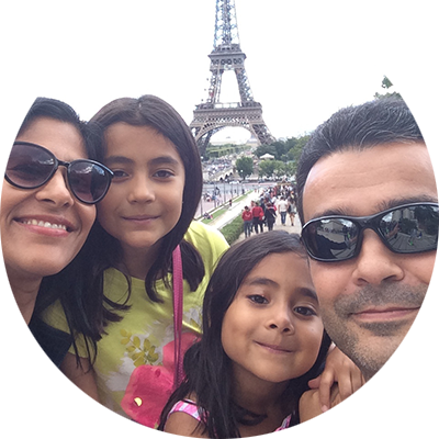 A man, woman and two young girls post together. The Eiffel Tower stands in the background.