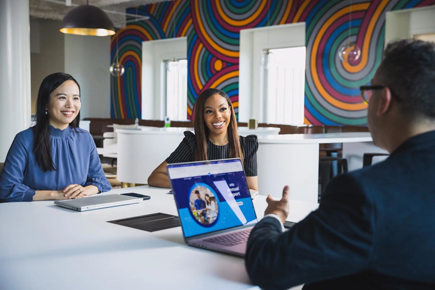 Three individuals seated at a table, engaged with a laptop, collaborating on a project or discussion.