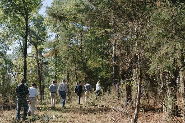 Participants of a pre-2020 tour of a forest outside of Ashdown, Arkansas hike through the forest.