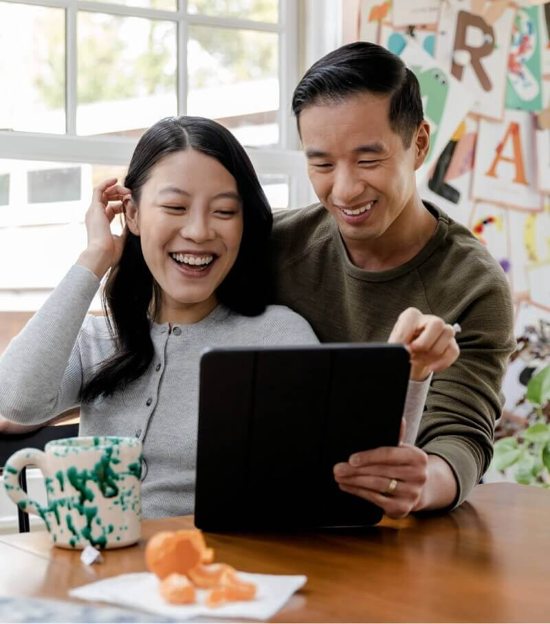 Image 43: A couple smiling while looking at a tablet