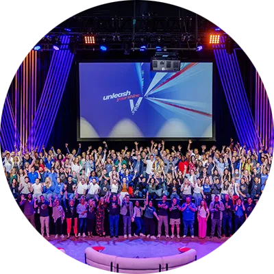 A large group of men and women gathered together on and in front of a large stage.
