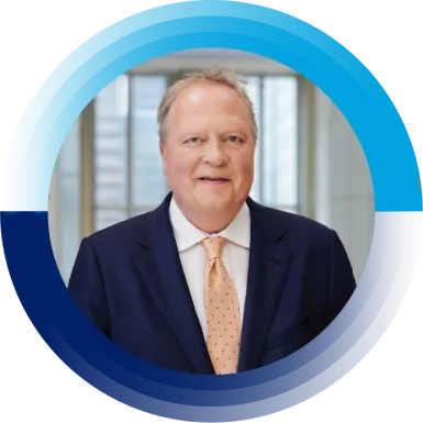 Jon R. Moeller, Charmin of the Board, President and Chief Executive Officer, is smiling at the camera. He is wearing a suit and a light orange tie.