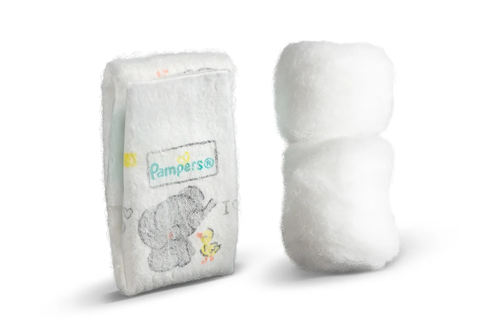 A Pampers Swaddlers Pxxs diaper next to two stacked cotton balls for size comparison.