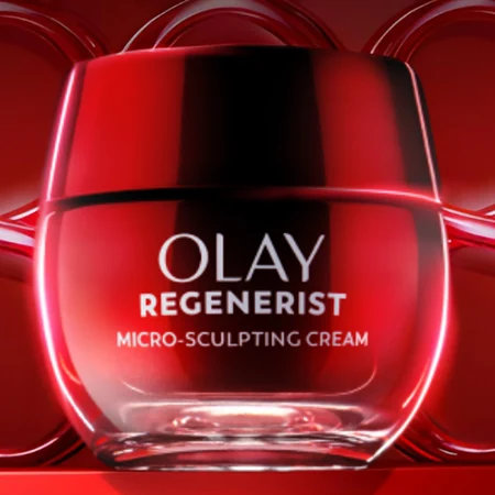 Red jar displayed against a red background with circular design elements. The words “Olay Regenerist Micro Sculpting Cream” are written on the front in silver