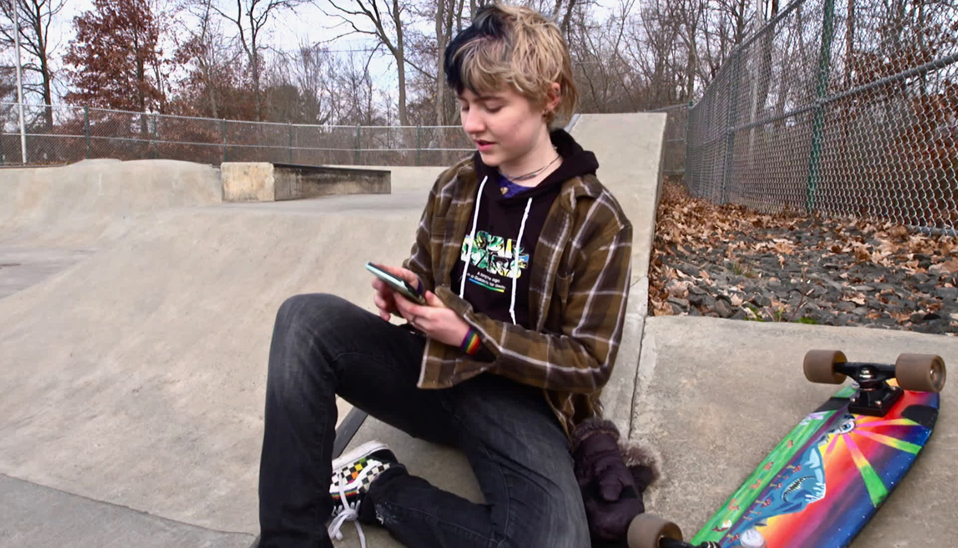 Gabby sits in the skatepark on her phone
