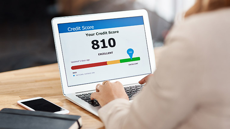 Photo of a woman back from behind with her laptop open to a website showing her credit score