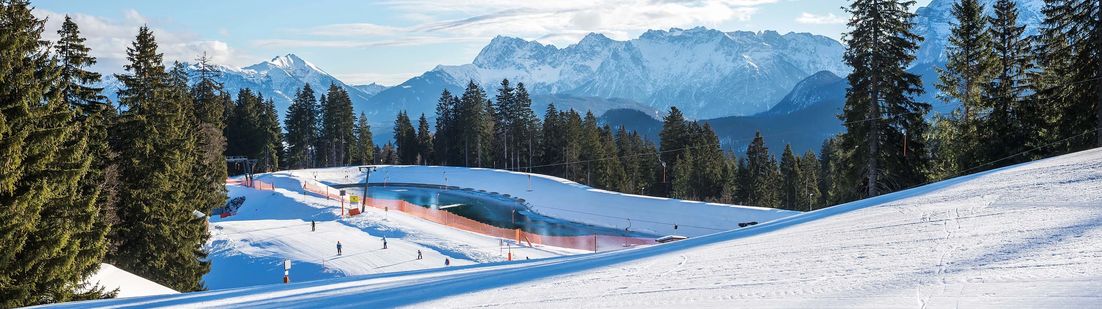 Skiers traverse the snow-packed slopes of Garmisch on a bright and clear day.