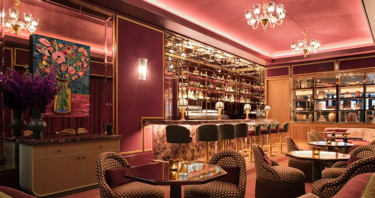Interior lounge shot of Brasserie Fouquet NYC, showing a full bar, comfy seats, and chandeliers.