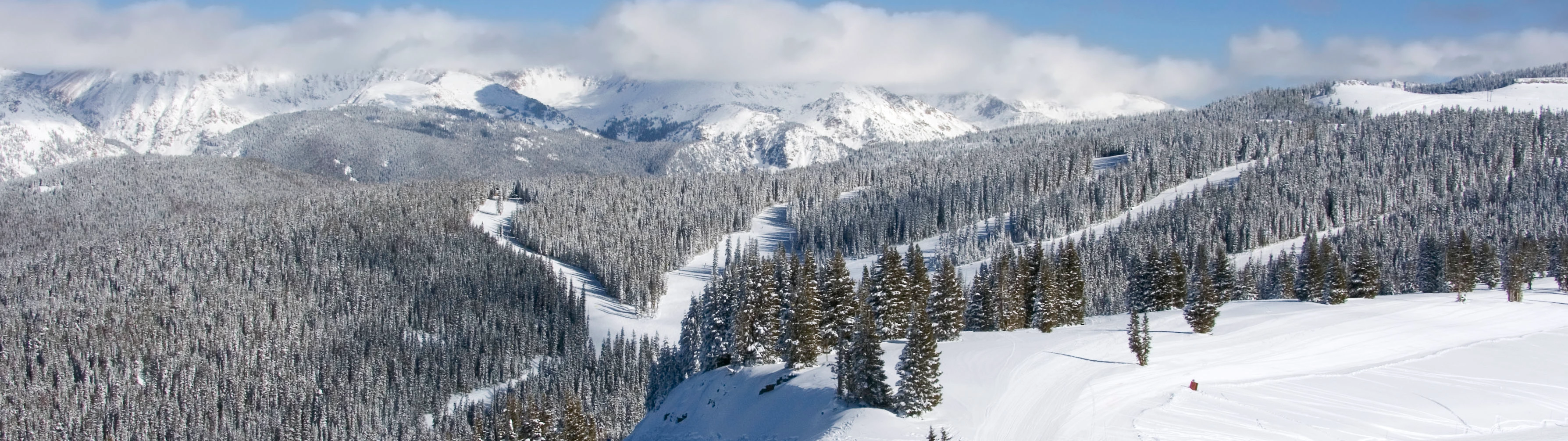 The rolling, snow-packed mountains of Vail on a clear day.