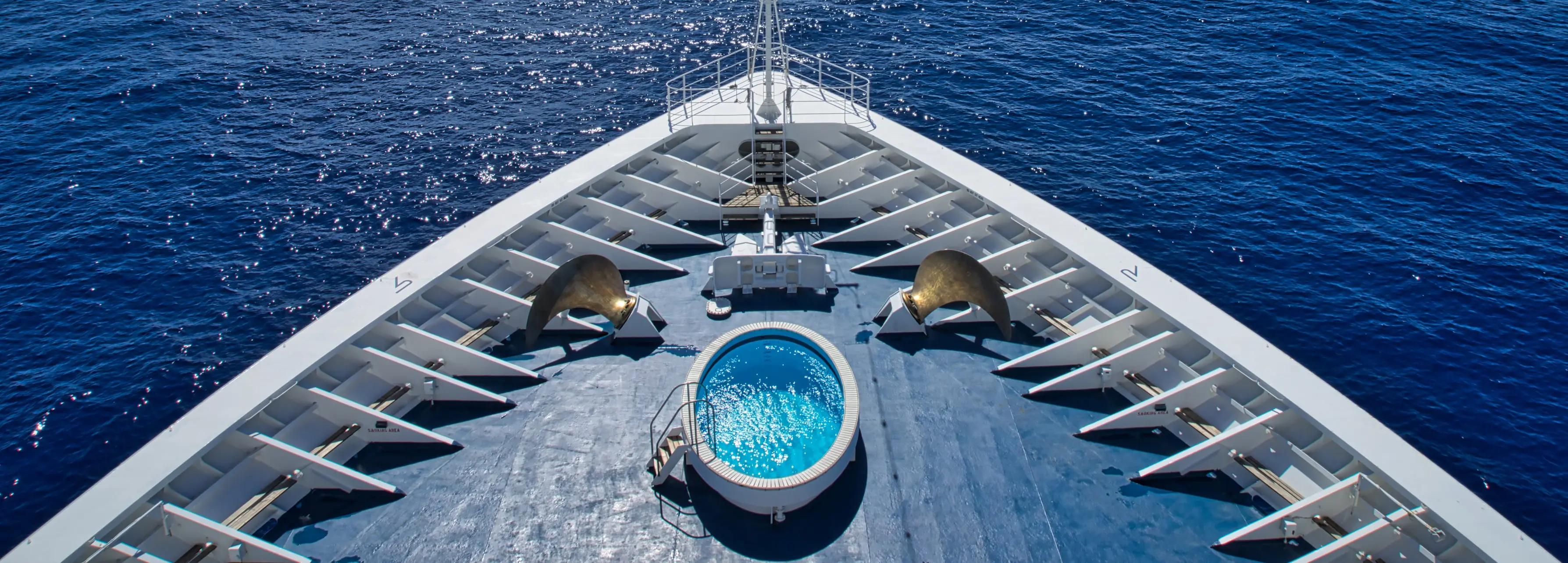 The bow of a luxury cruise liner shot from above with a jacuzzi and the Indian Ocean in the background.