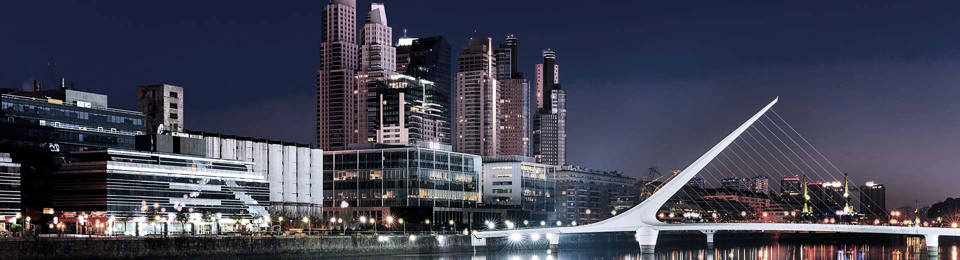 The imposing skyline of Buenos Aires lit up at night, with skyscrapers piercing the sky.
