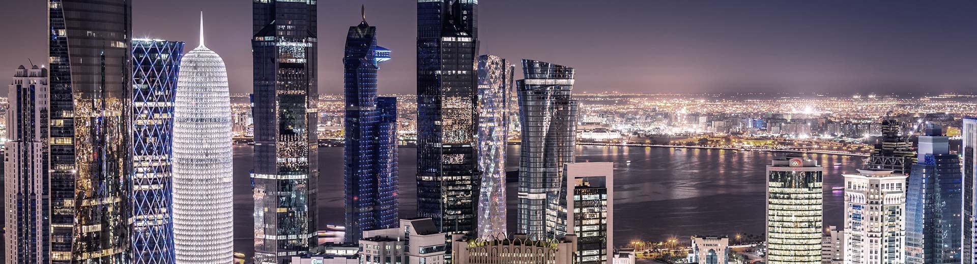 The varied and imposing skyscrapers of Doha pierce the nightsky .