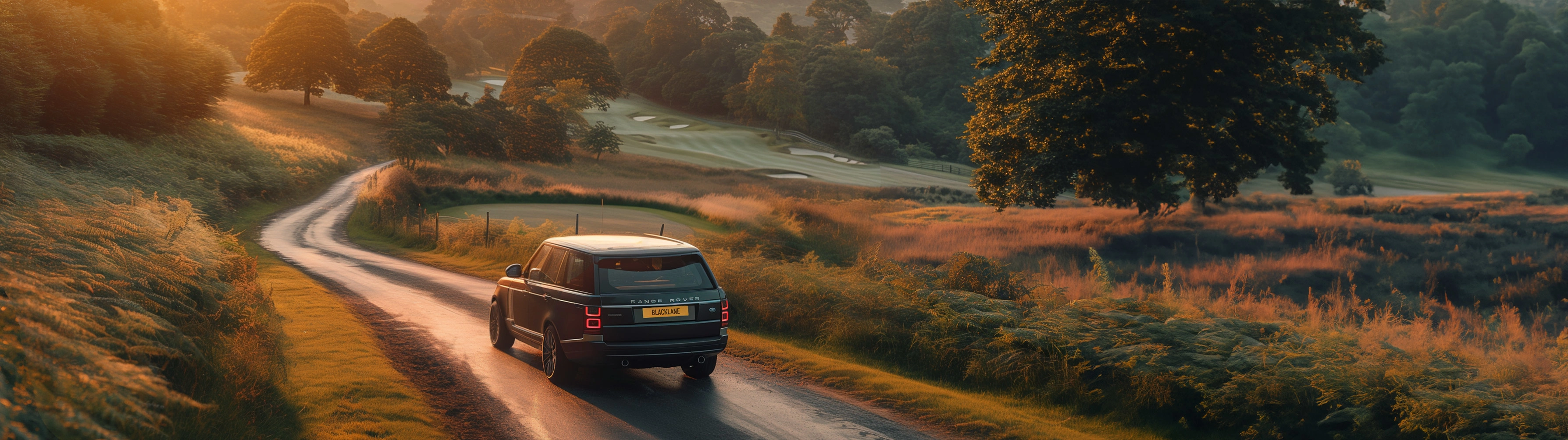 A Blacklane Range Rover speeds through the English countryside at sunset on the way to a golf course in the distance.