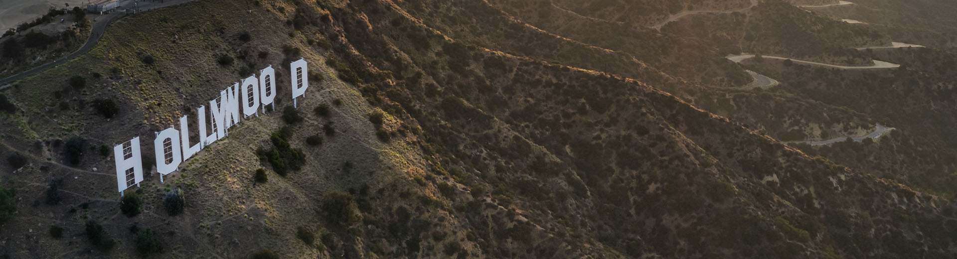 Rolling green hills and the world-famous Hollywood sign dominate the dusk light.