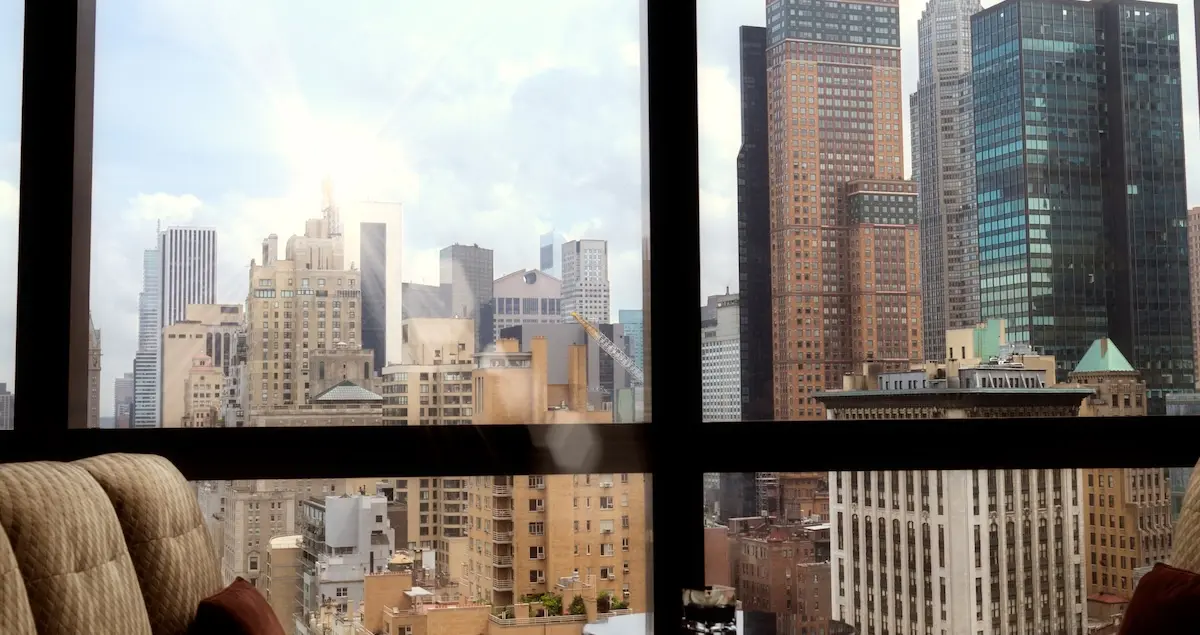 View of a dining table and chairs in a New York skyscraper, with the NYC skyline visible out the window.