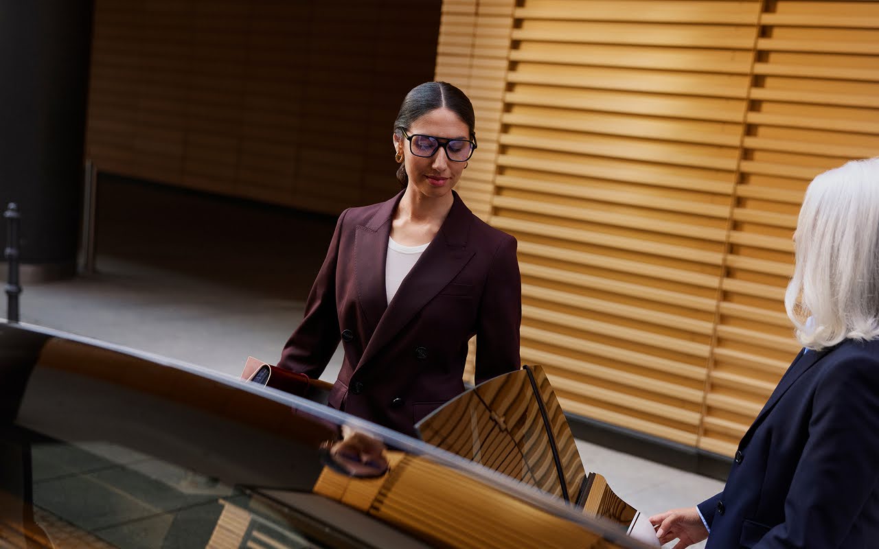 A Blacklane chauffeur helps her smartly dressed passenger enter the limousine.