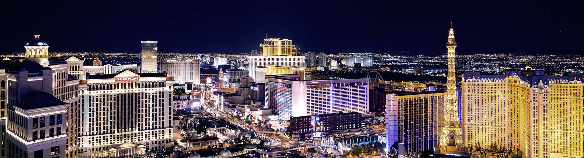 The famous Las Vegas strip lit up at night, with toweing casinos and streets filled with cars.