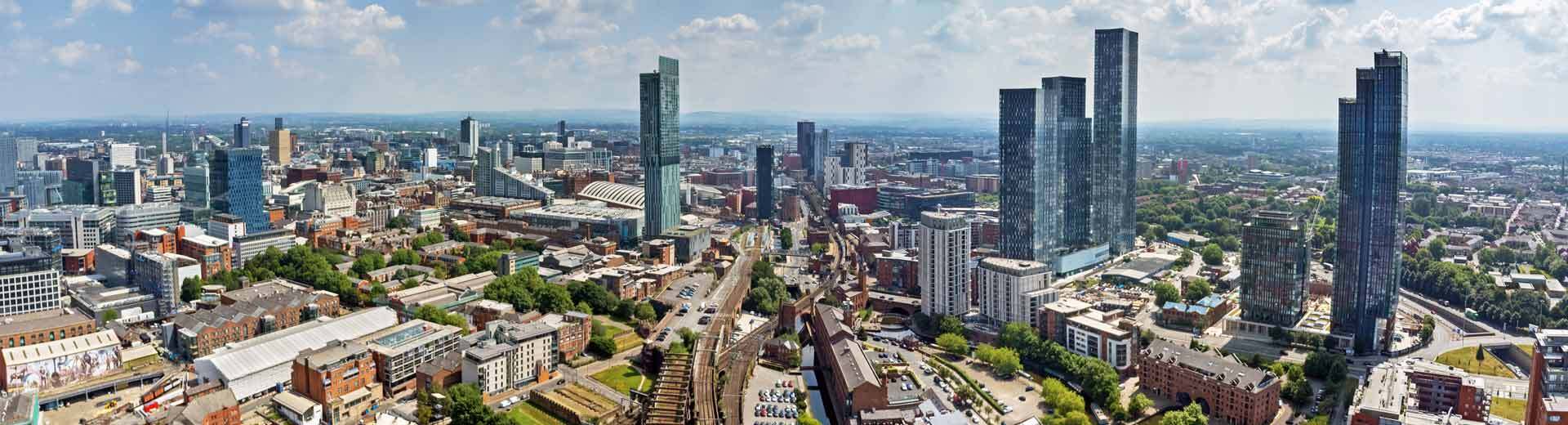 Aerial view of Manchester, with skyscrapers towering over red-brick Victorian buildings.