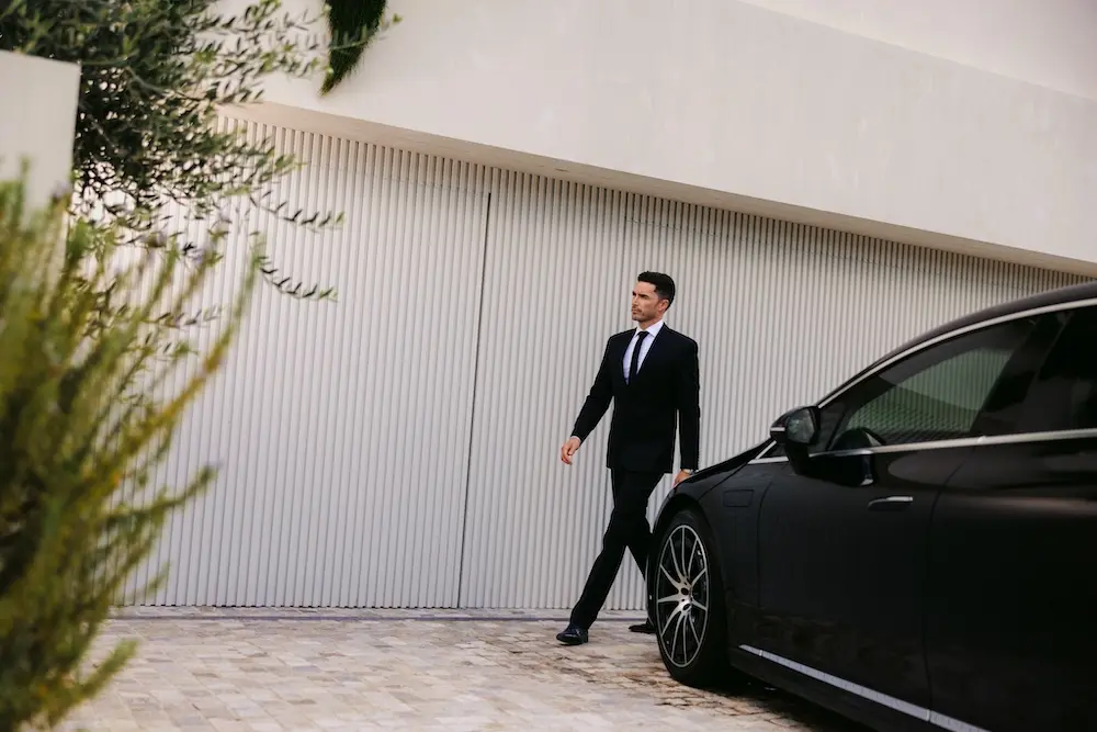 A Blacklane chauffeur smiles while walking around his Mercedes-Benz EQS.