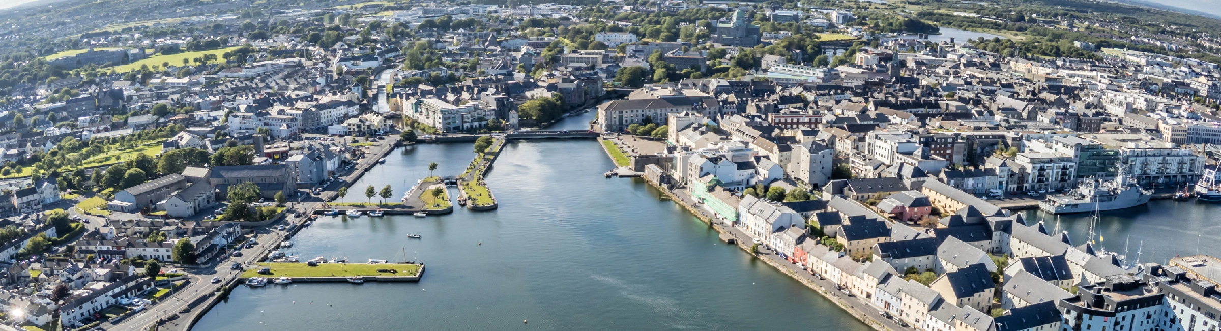 An ariel view on a sunny day of the beautiful coastal town of Galways, with the harbor and town center visible.