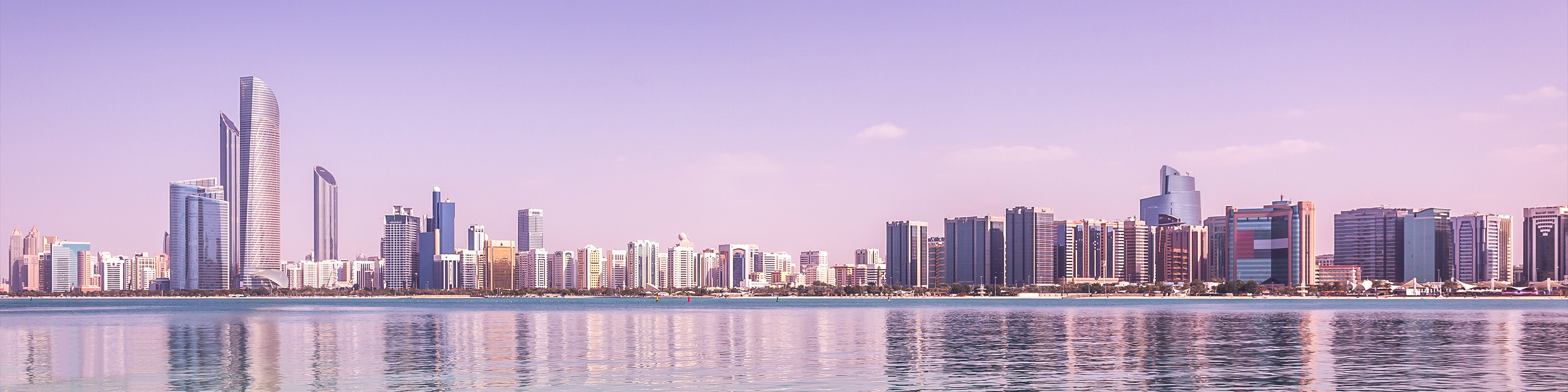 Die weitläufige Skyline von Dubai vor dem Hintergrund des lila Lichts von Dämmerung oder Morgendämmerung.
