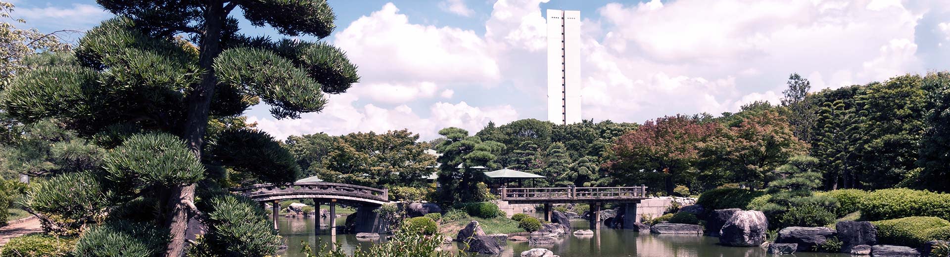 A traditional, green Japanese garden dominates the image, with a single white building looming in the background.