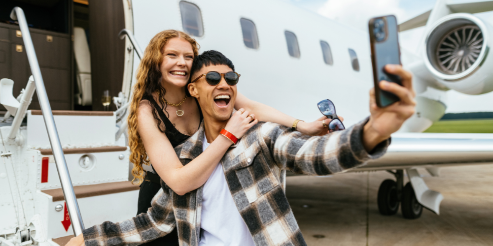 Happy couple capturing a luxury travel moment in front of a private jet.