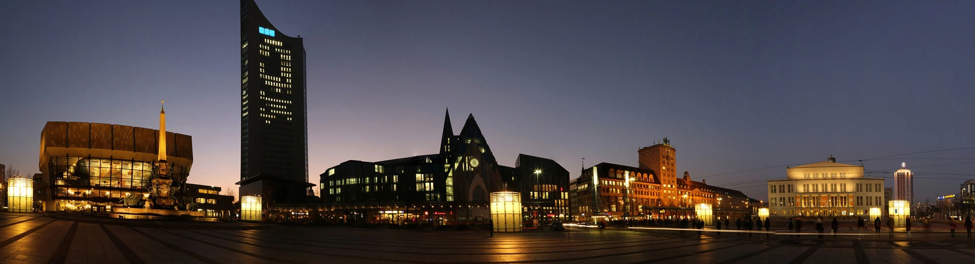 The skyline of Leipzig silhouetted against the black sky at night.