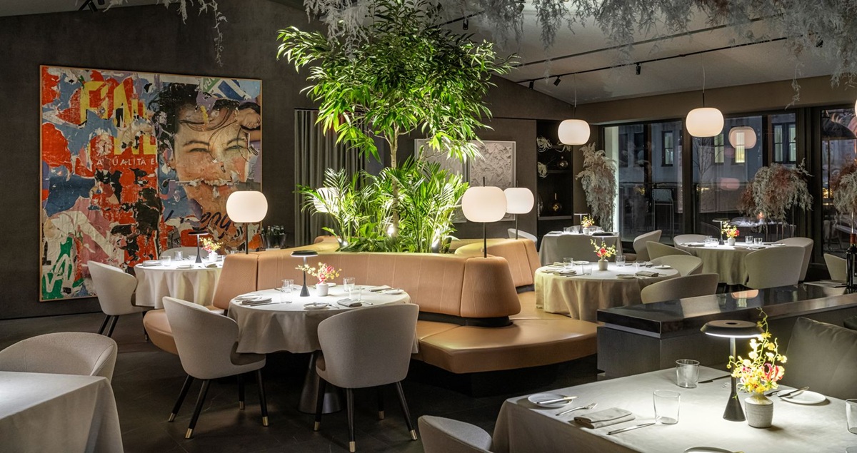The exquisite interior of the dining room at the Core Club NYC private members club, showing low lamplighting, set tables and hip art.