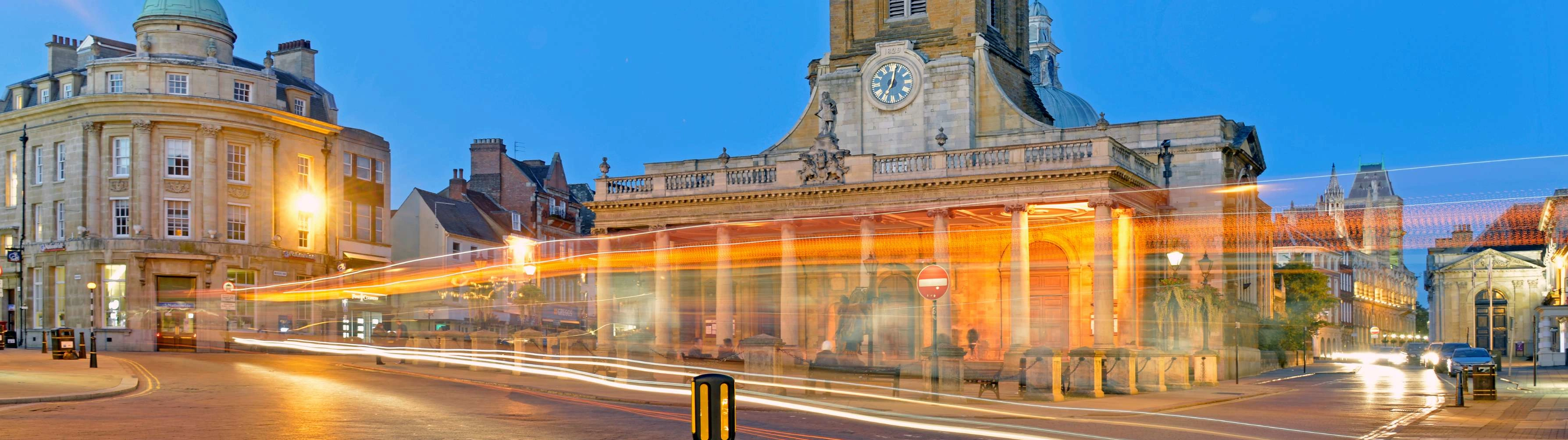 The streets of Northampton are illuminated by passing traffic in the evening.