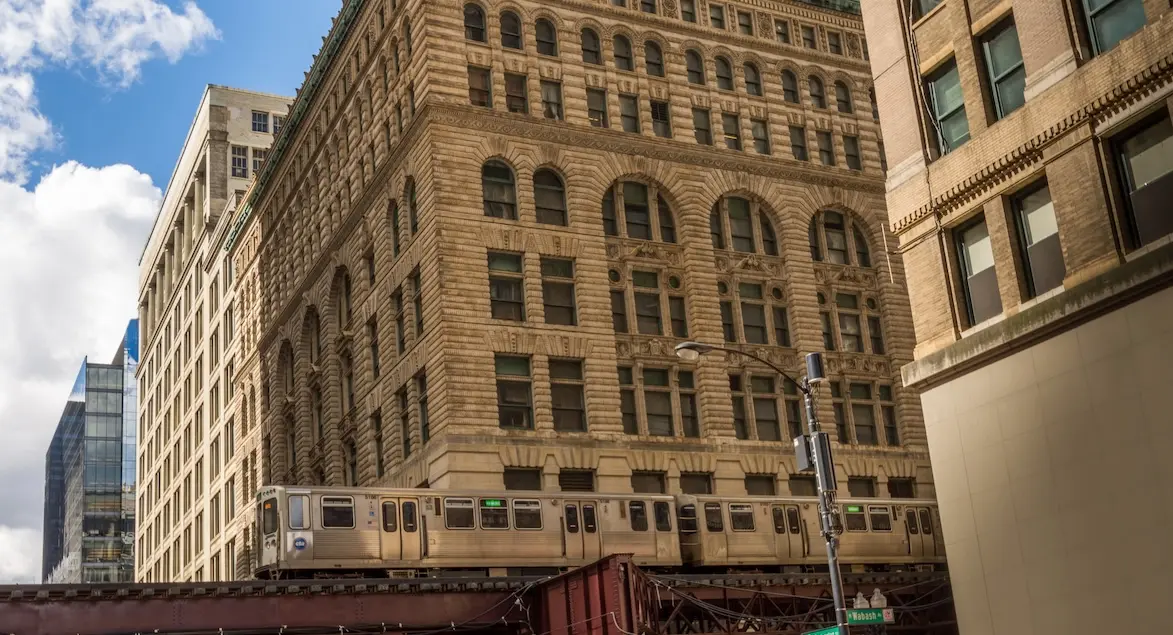 Exterior of Chicago downtown buildings with an El train rolling in the foreground.