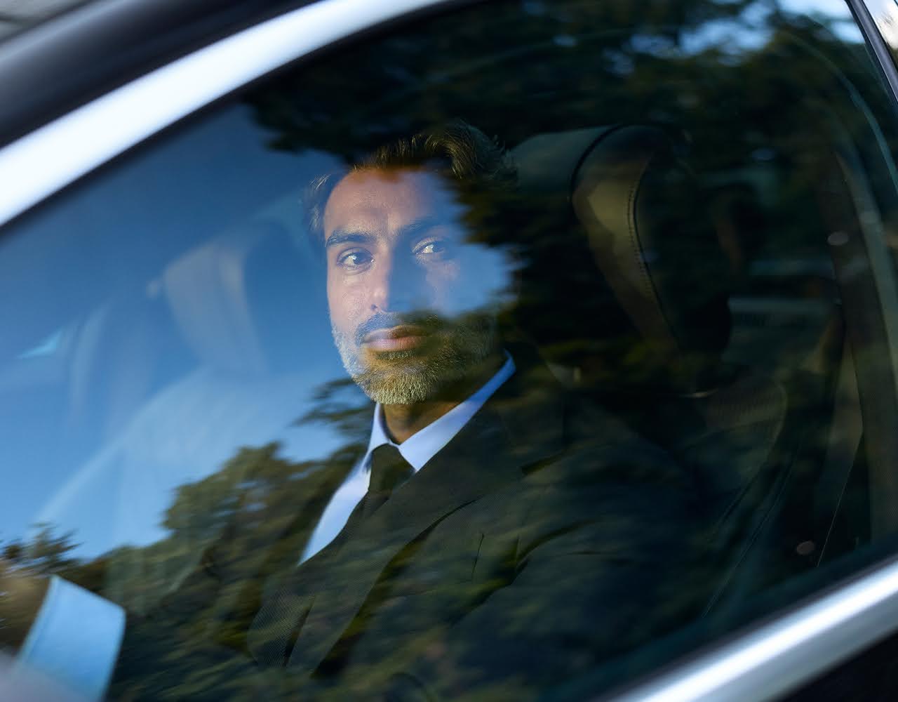Shot of a Blacklane chauffeur looking out through the driver's window of a limousine.