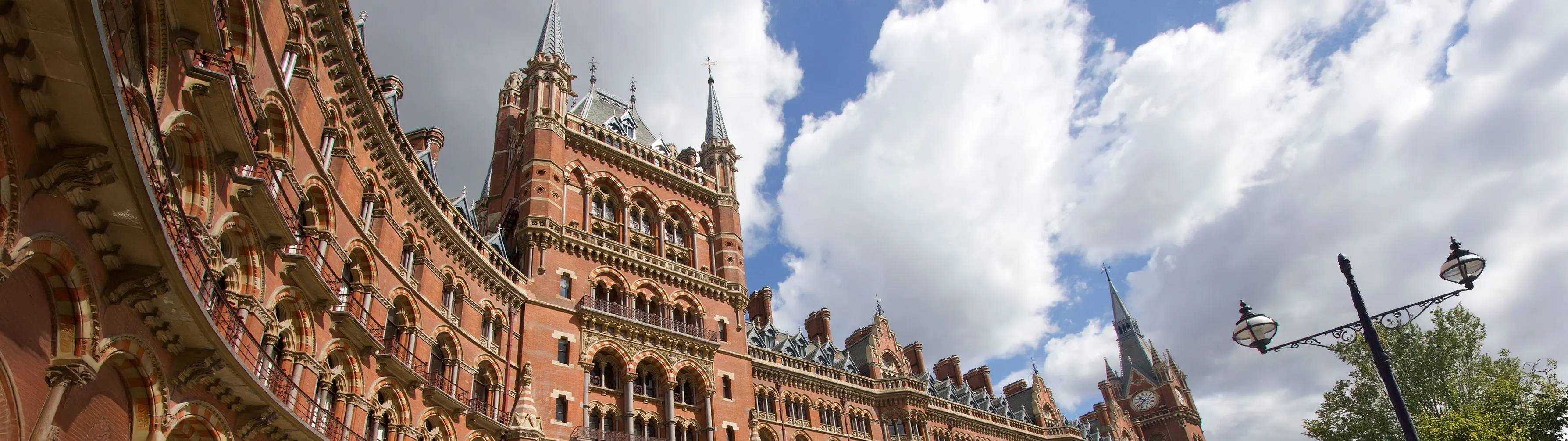 The ornate exterior of London St Pancras station under a cloudy sky.