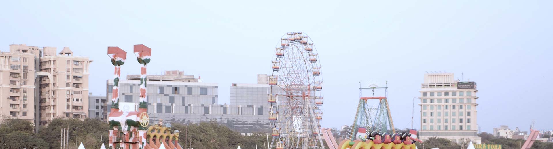 A funfair in the foreground of Faridibad on a clear and warm-looking day
