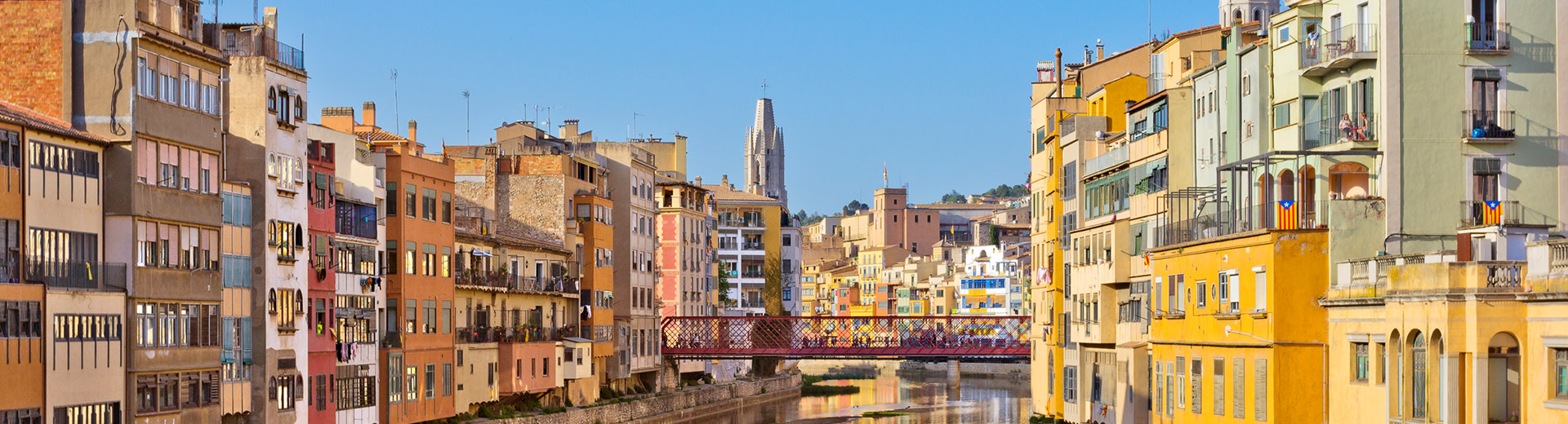 The beautiful bright colours of Girona on a clear and sunny day, overlooks a canal or waterway.