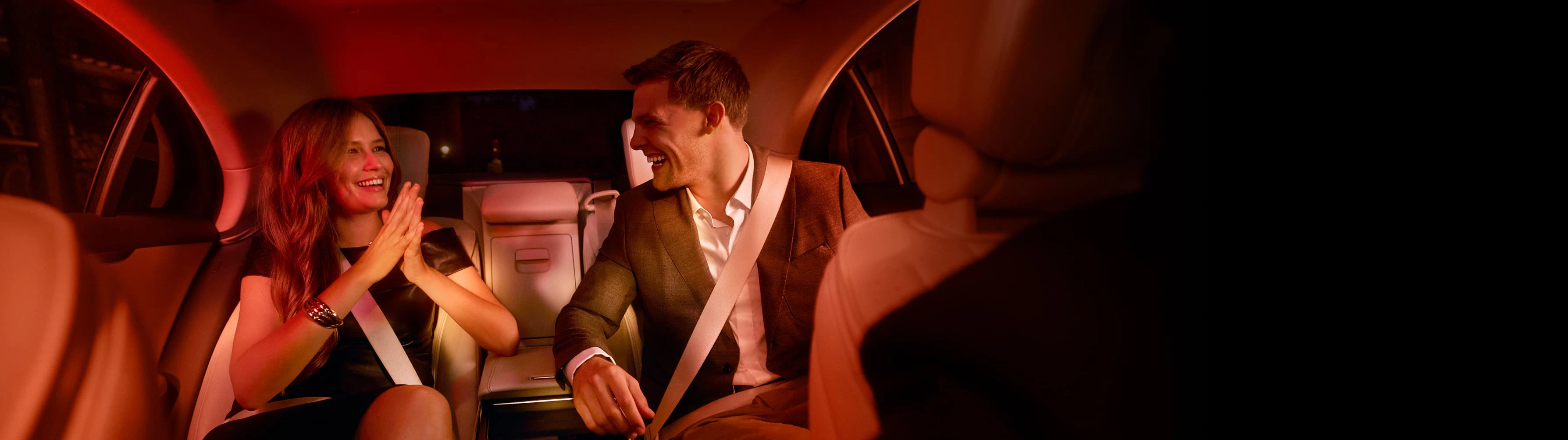 A stylish couple laugh in the backseat of a Blacklane limousine service.