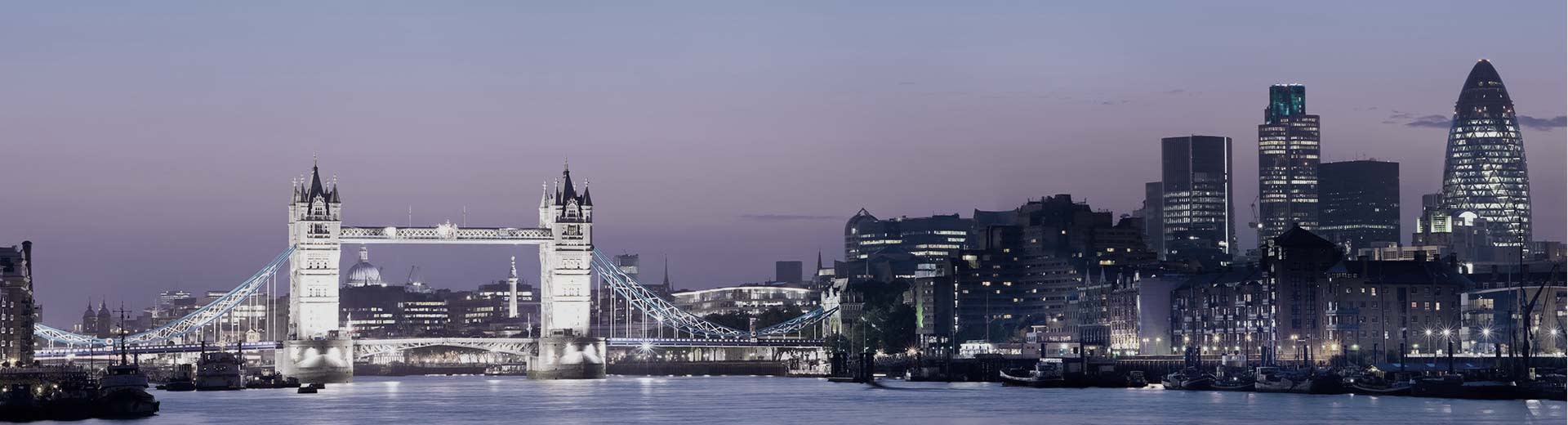 Die London Bridge erstreckt sich nachts über die Themse und beleuchtet den Himmel.