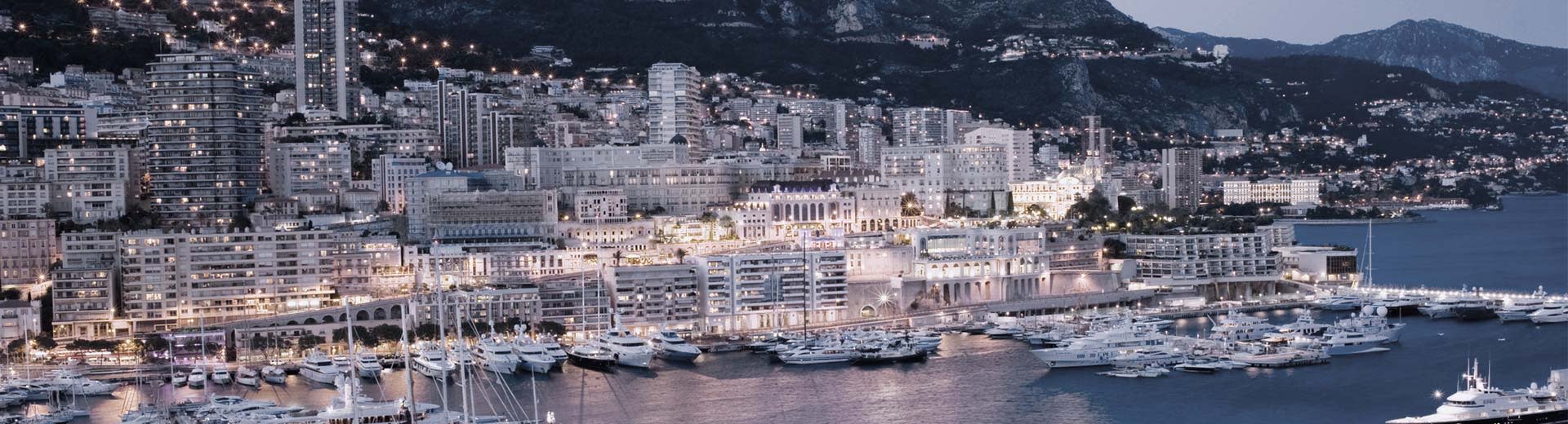 The tightly packed, white buildings of Monaco stretch along the shoreline.