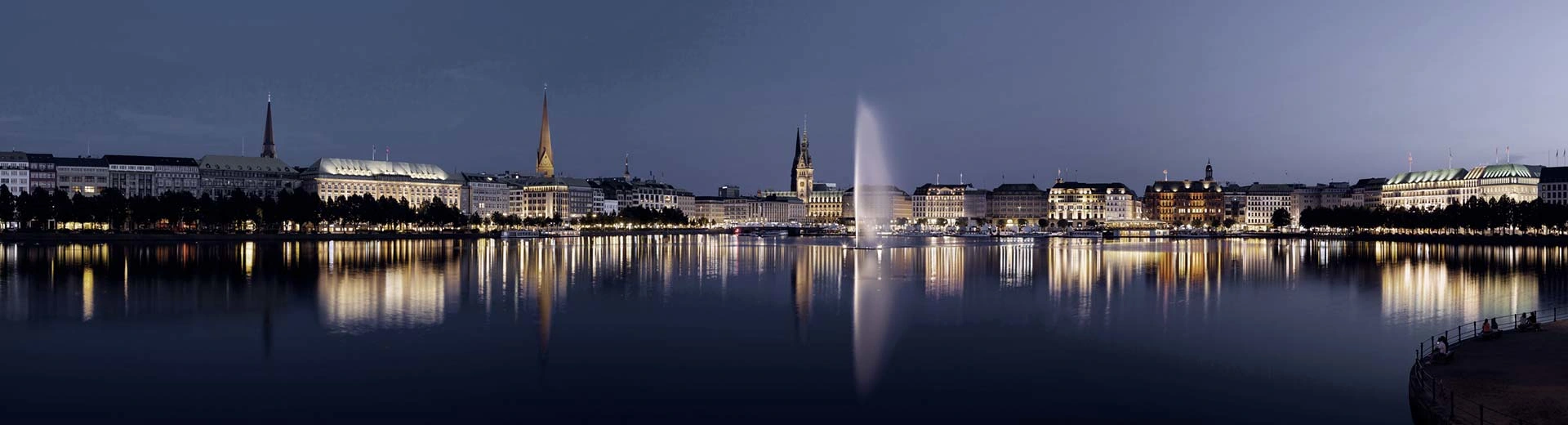 Le port de Hambourg s'est allumé la nuit Agaisnt un ciel bleu foncé.
