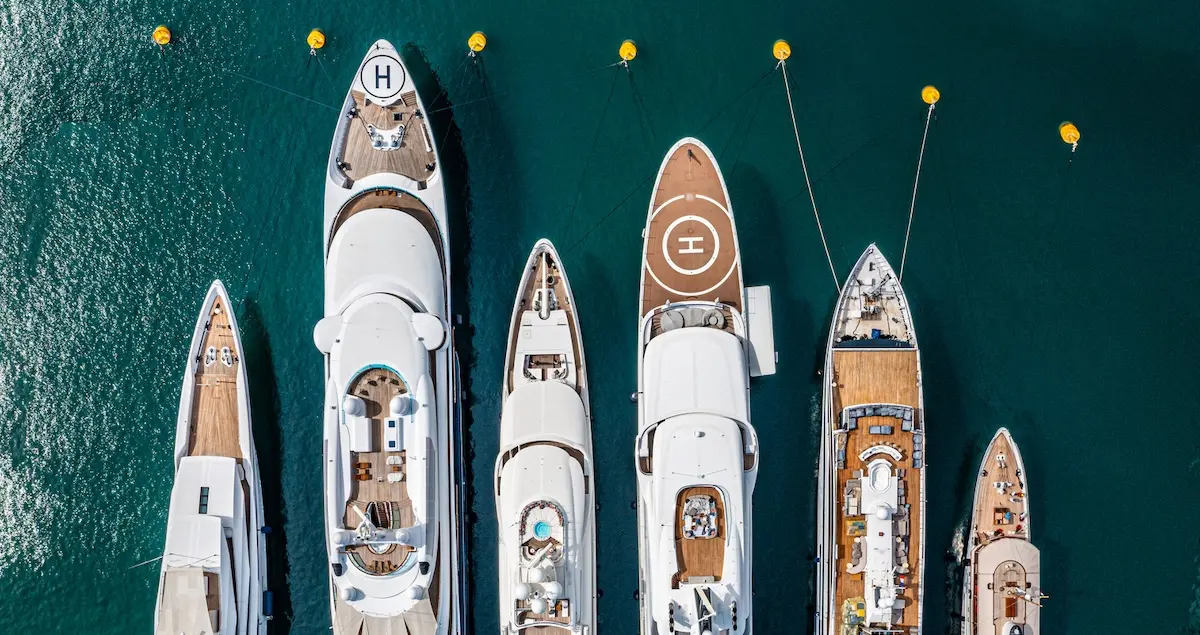 Overhead shot of 6 superyachts at the Monaco Yacht Show, tied up with yellow buoys.