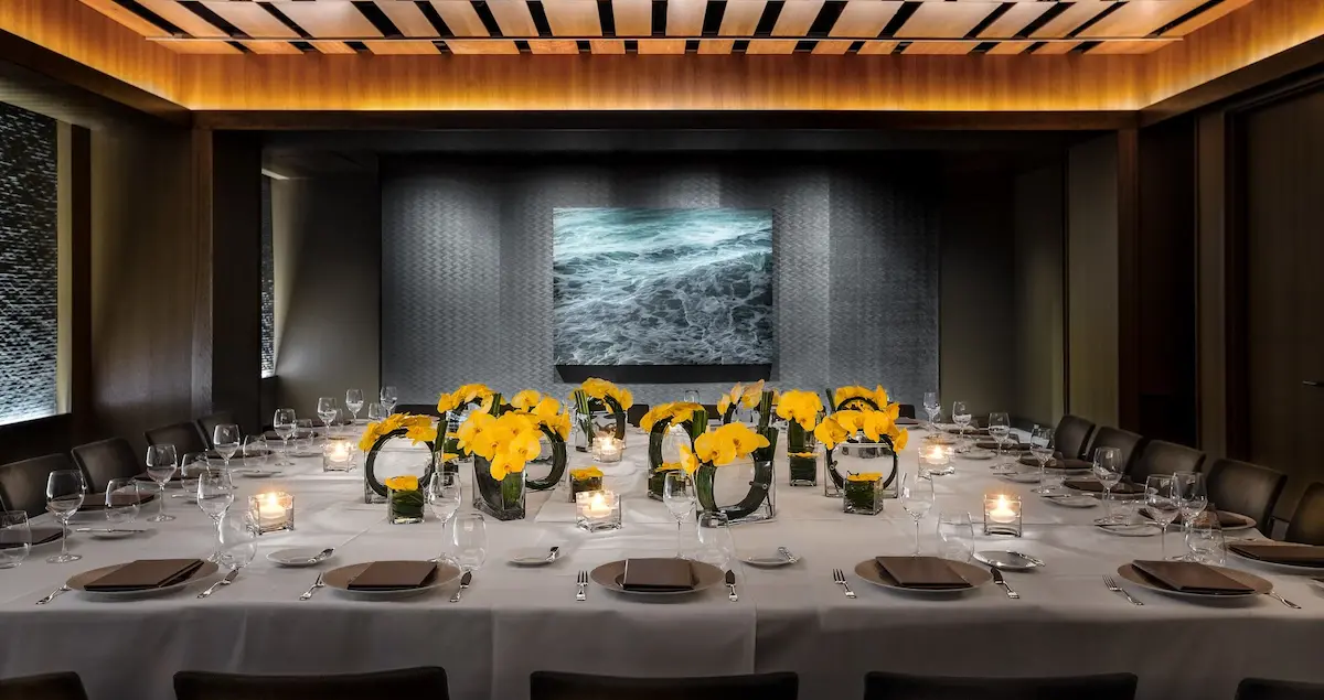 The private dining room of the Le Bernardin restaurant in NYC with the lighting soft and the table laid.