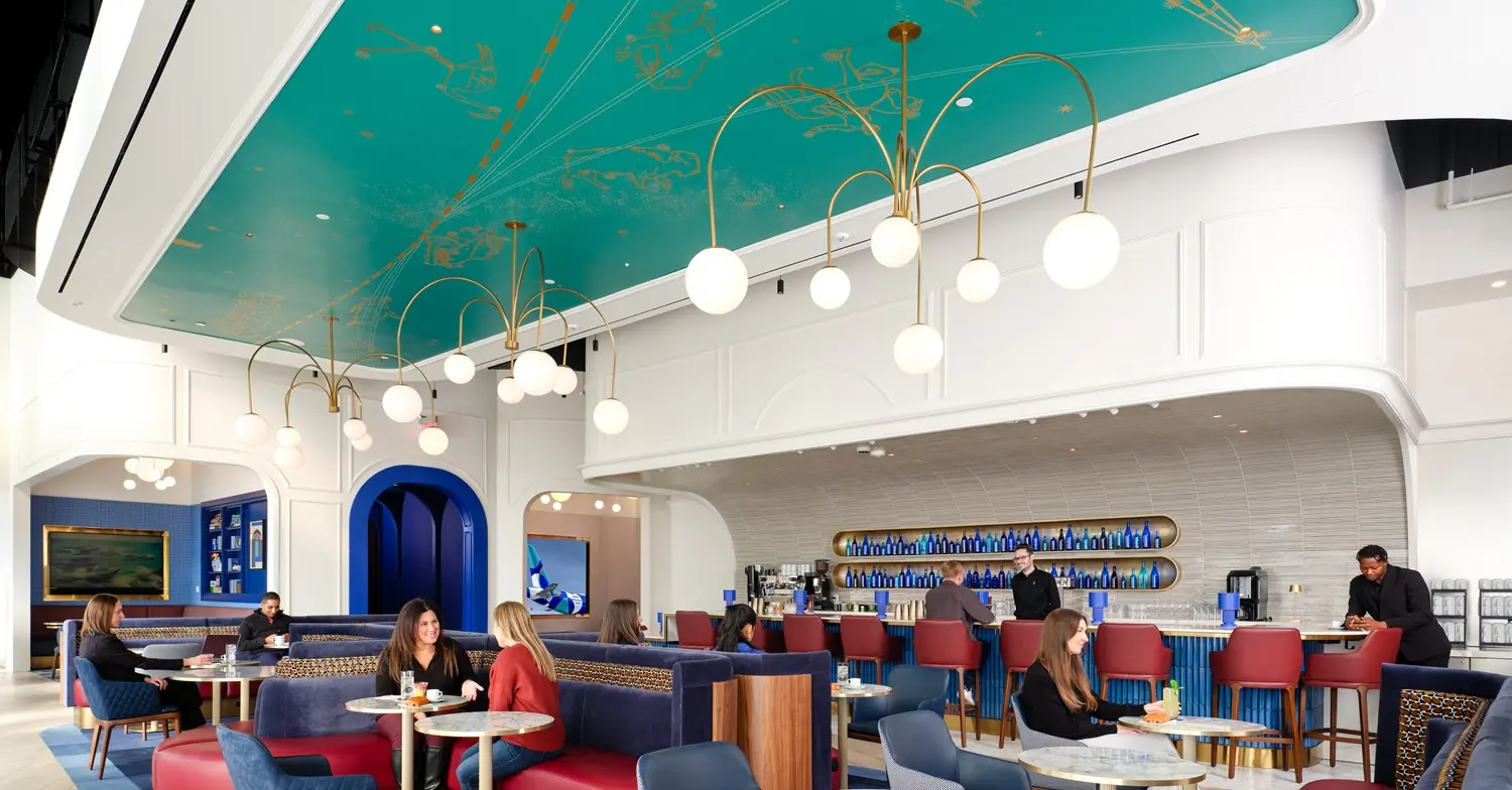 Shot of the new JetBlue BlueHouse airport lounge in JFK Airport, with customers sitting around a bar area.