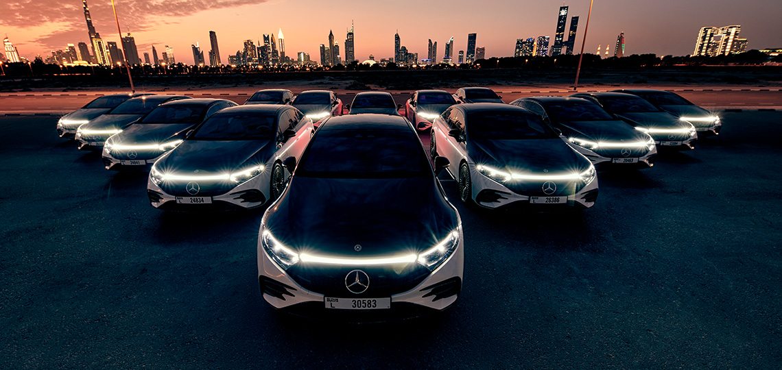 A fleet of Mercedes-Benz EQS vehicles with the Dubai skyline in the background.