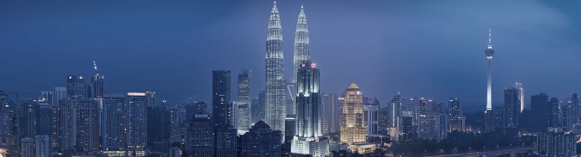 The looming twin towers of Kuala Lumpur light up the dark sky.
