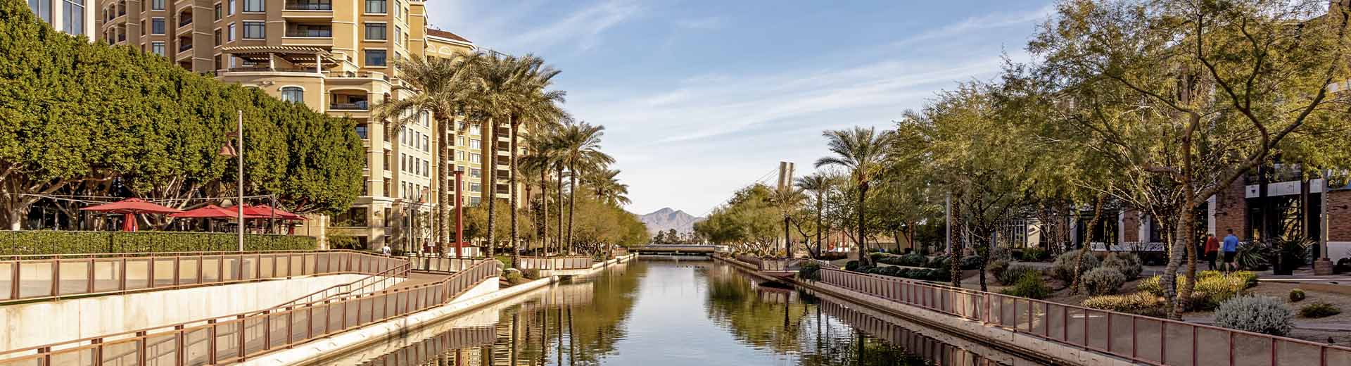 A waterway in Scottsdale on a clear summer's day, lined by low-rise residential buildings.