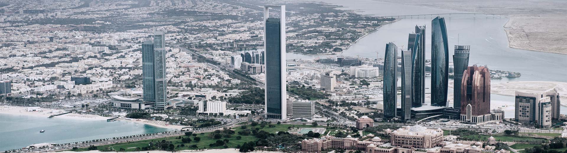 Panorama of Abu Dhabi's city center with a clear view of skyscrapers and desert in the background.