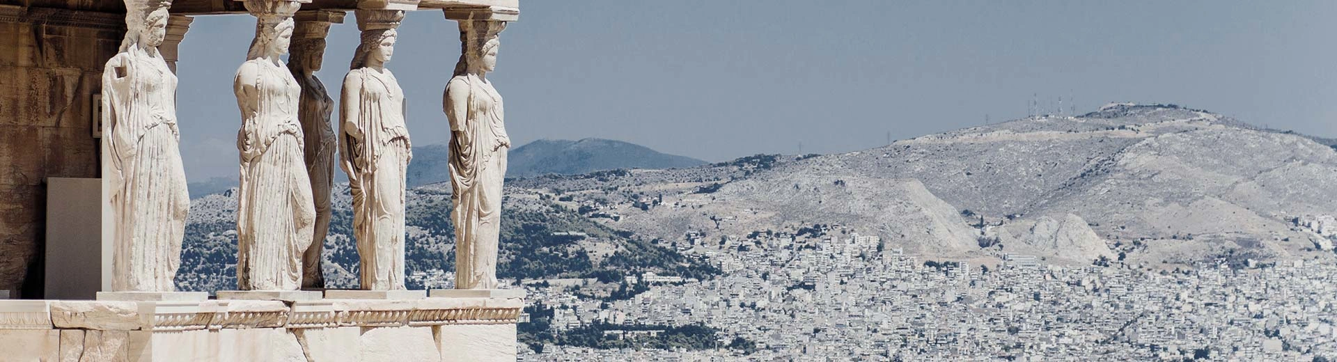 Caryatids of the Erechtheion in Athens with mountains in the background.